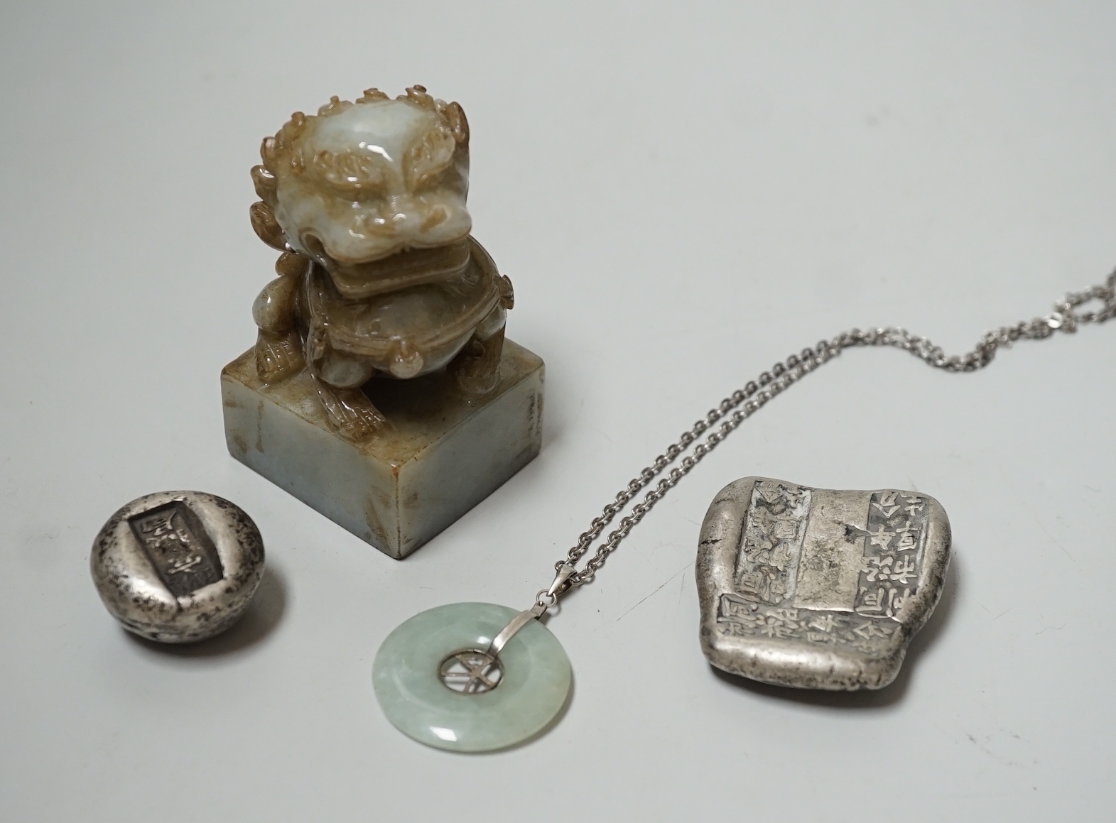 A Chinese jadeite lion-dog seal (black matrix), a similar pendant and two ingots